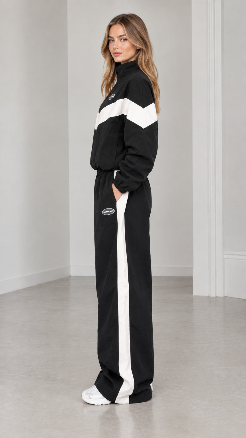 Side profile of woman in black zip-up jacket and wide leg pants with white side stripe
