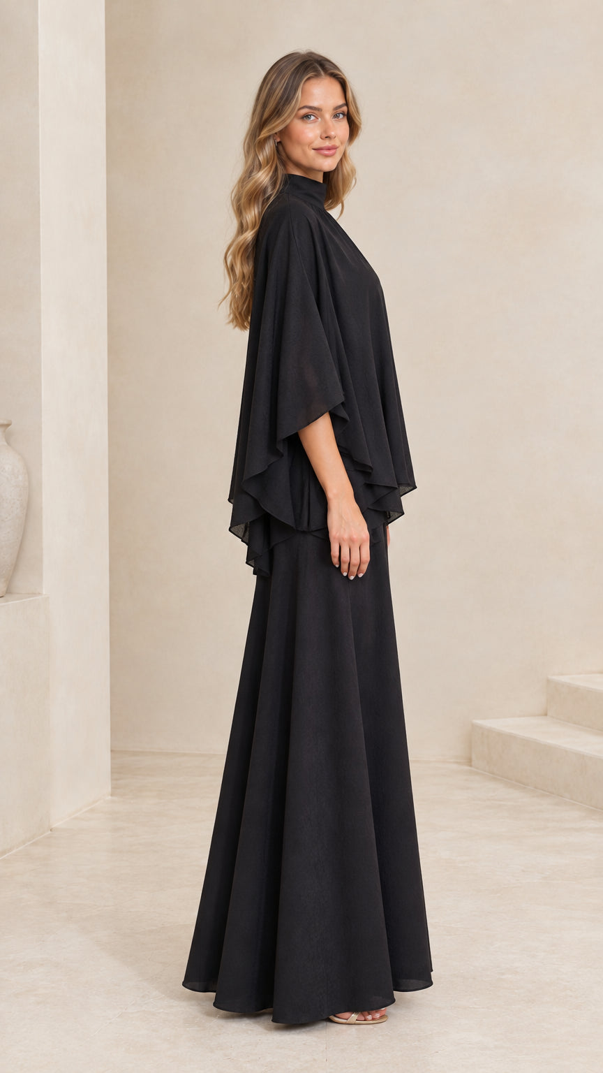 Side profile of woman in flowing black tiered cape maxi gown