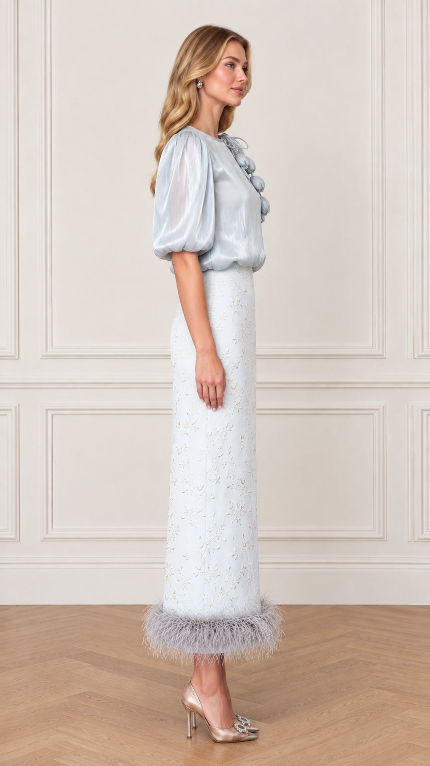 Side profile of model in Ice Blue evening top and feather trim maxi skirt
