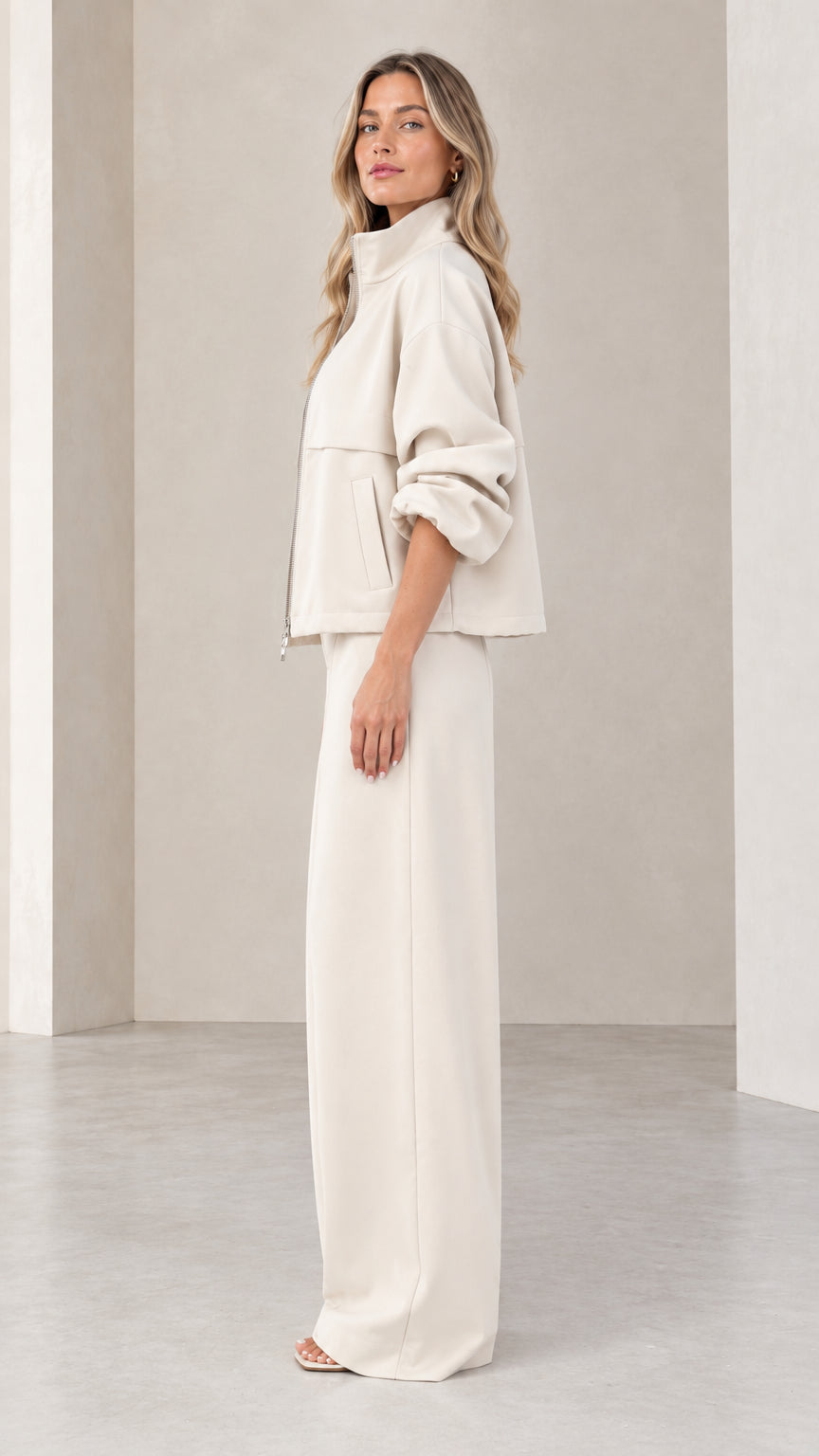 Side profile of woman wearing beige matching track jacket and wide-leg pant set
