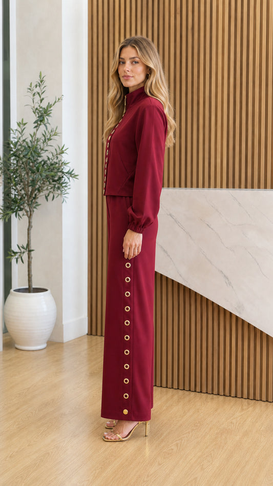 Side profile view of model in burgundy pants set showing side gold eyelet details