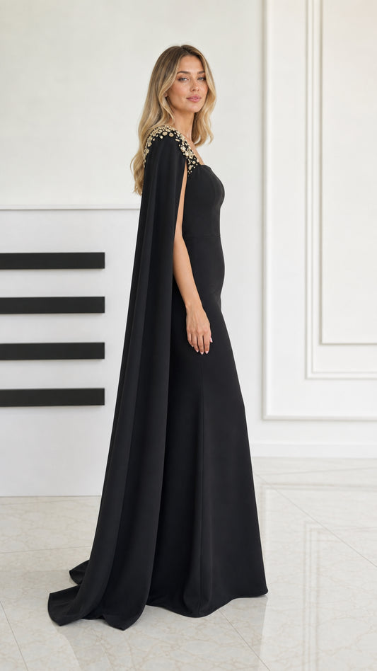 Side profile of black cape sleeve evening gown showing elegant floor length drape