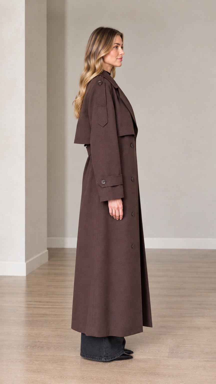 Side profile view of woman wearing brown maxi trench coat