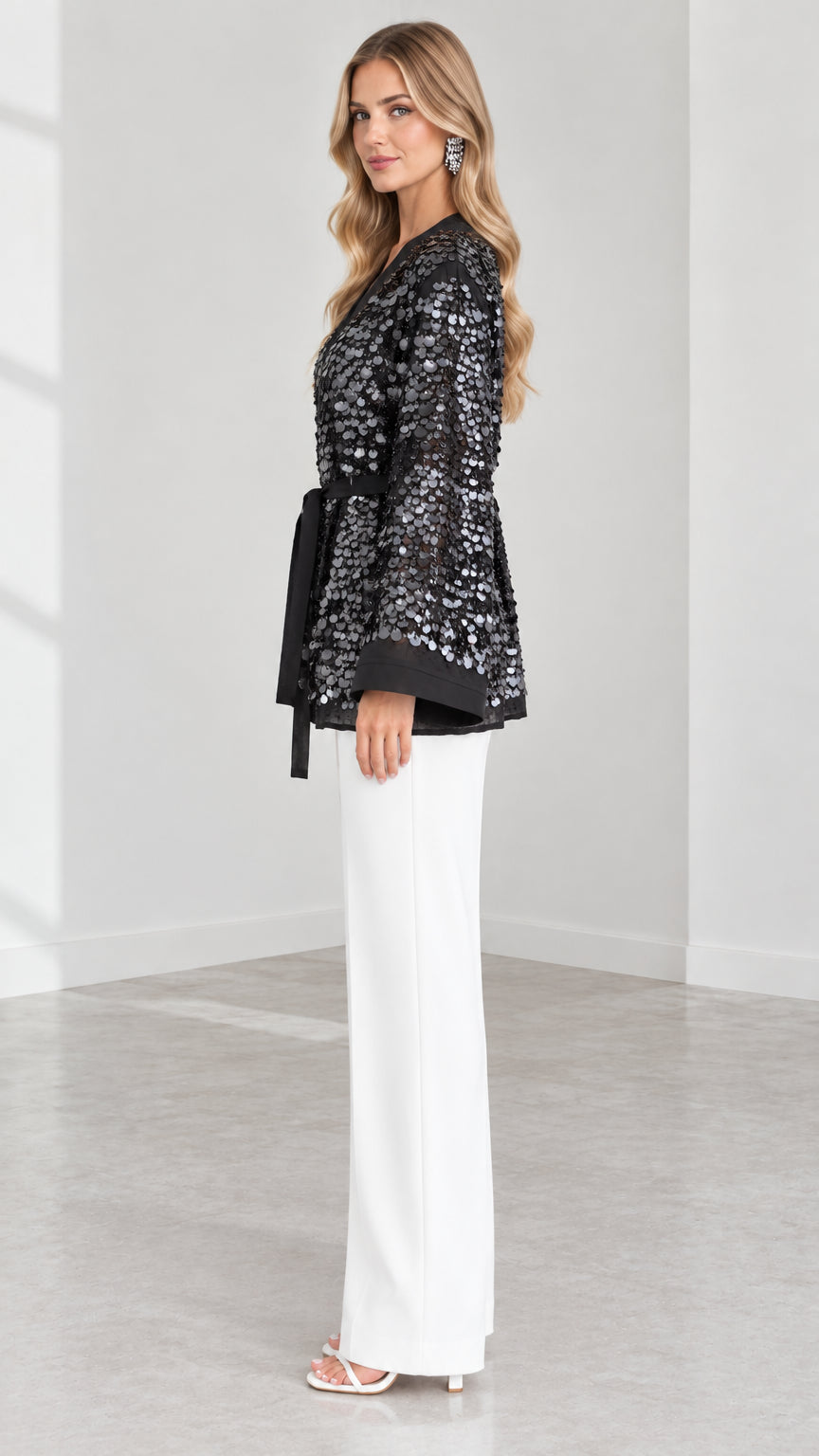 Side angle of model in Black sequin wrap cardigan showing sleeve and waist tie detail