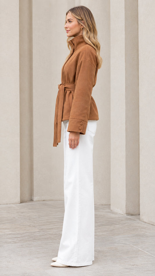 Side view of model wearing camel belted short coat and white wide leg pants