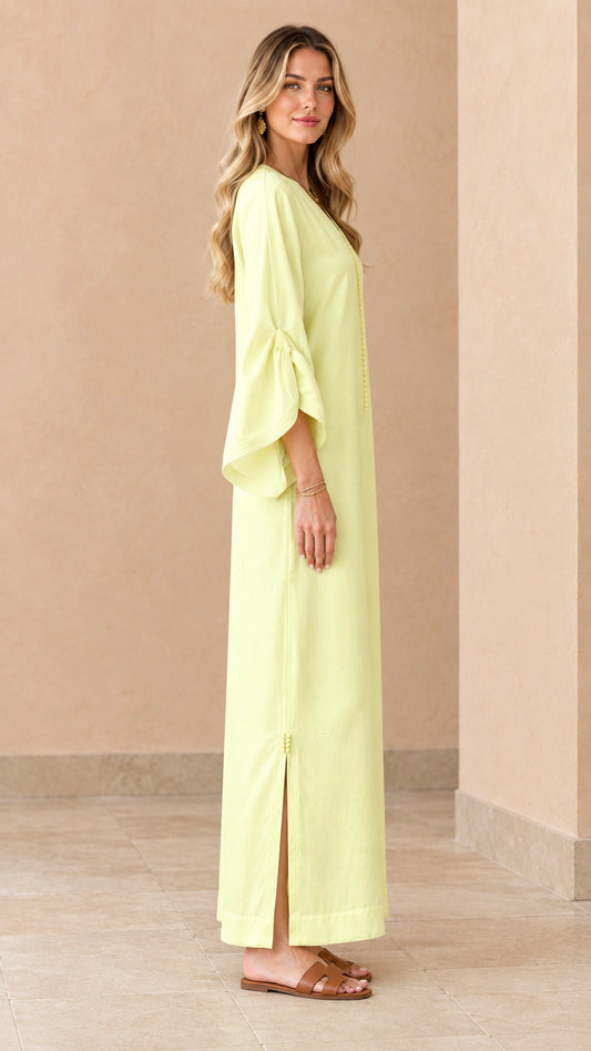 Side profile of woman wearing pale yellow relaxed kaftan dress with side slit