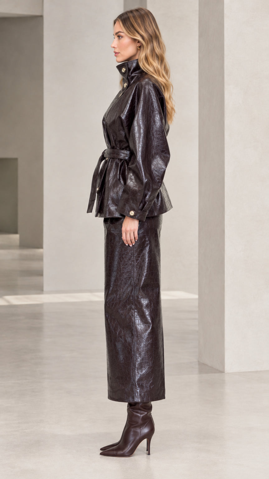 Side profile of woman in Dark Brown croc-embossed faux leather two-piece jacket and skirt set