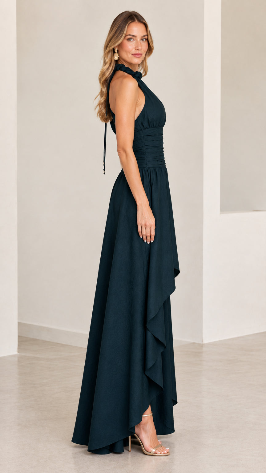 Side profile of model in dark green sleeveless high-low formal dress