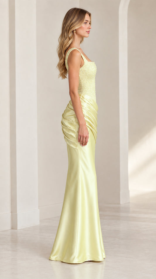 Side profile view of model wearing pastel yellow ruched satin evening dress
