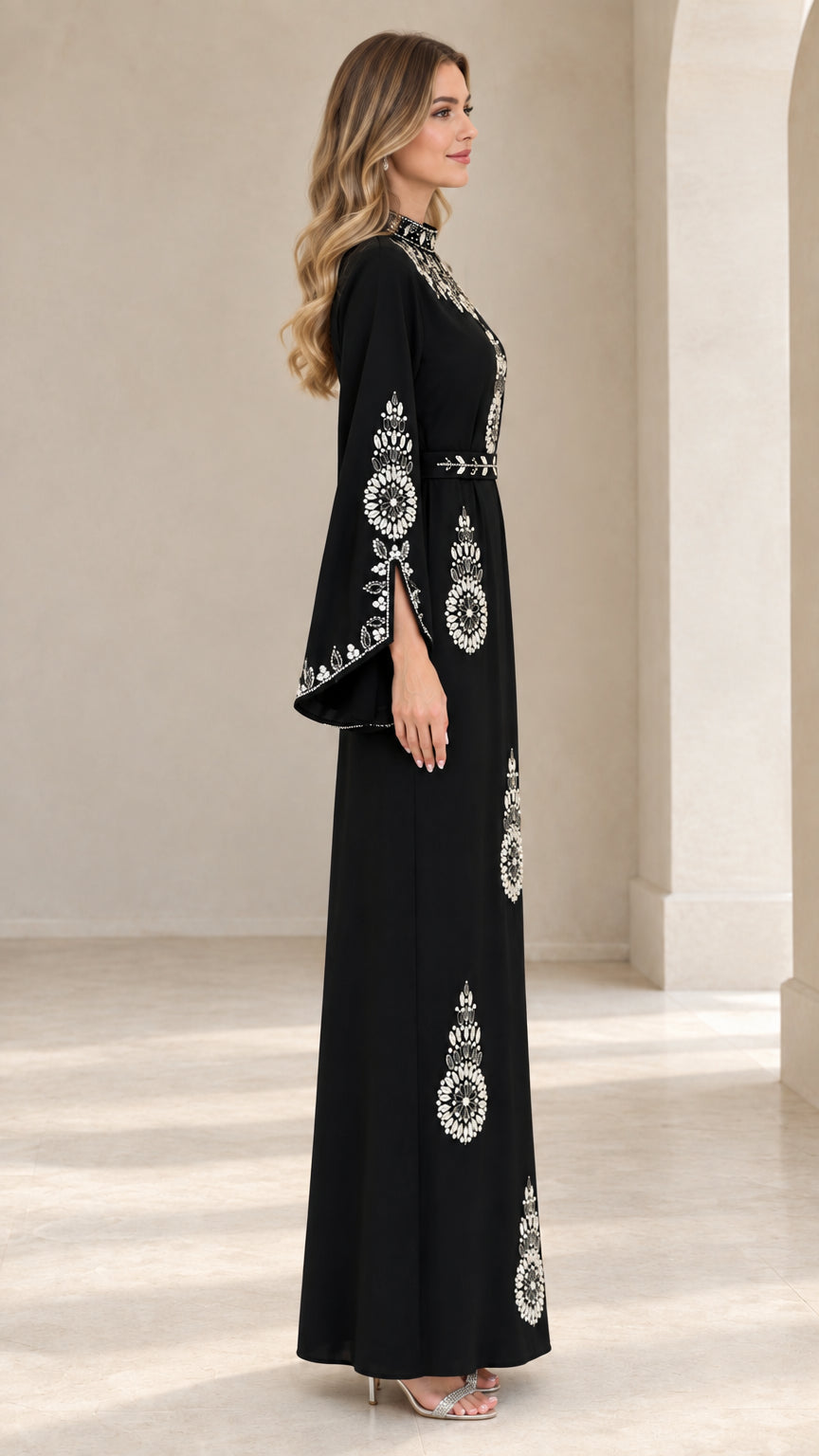 Side angle view of woman in black crystal embellished long sleeve maxi dress