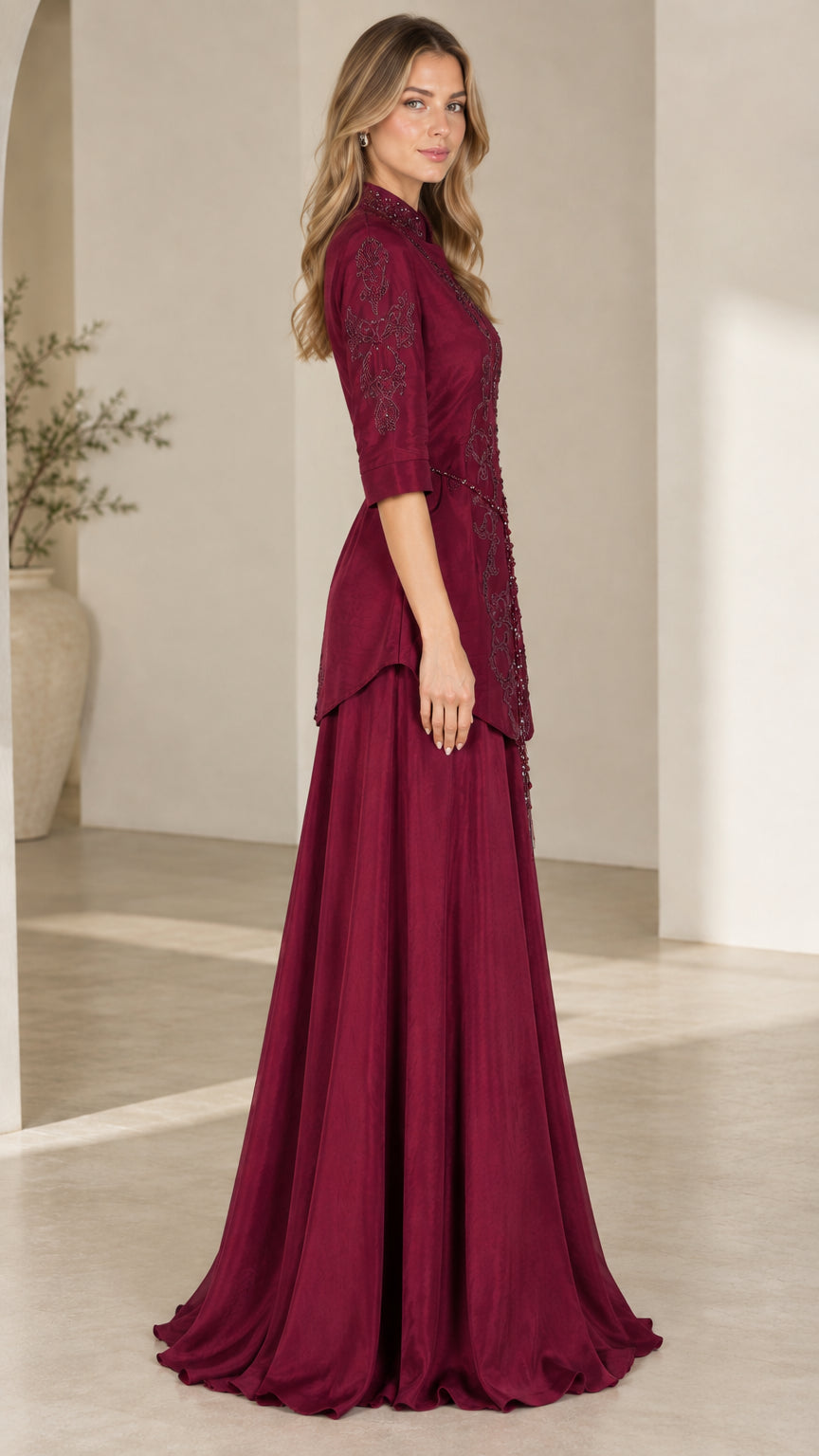 Side profile of burgundy beaded evening gown showing tunic overlay and flared skirt