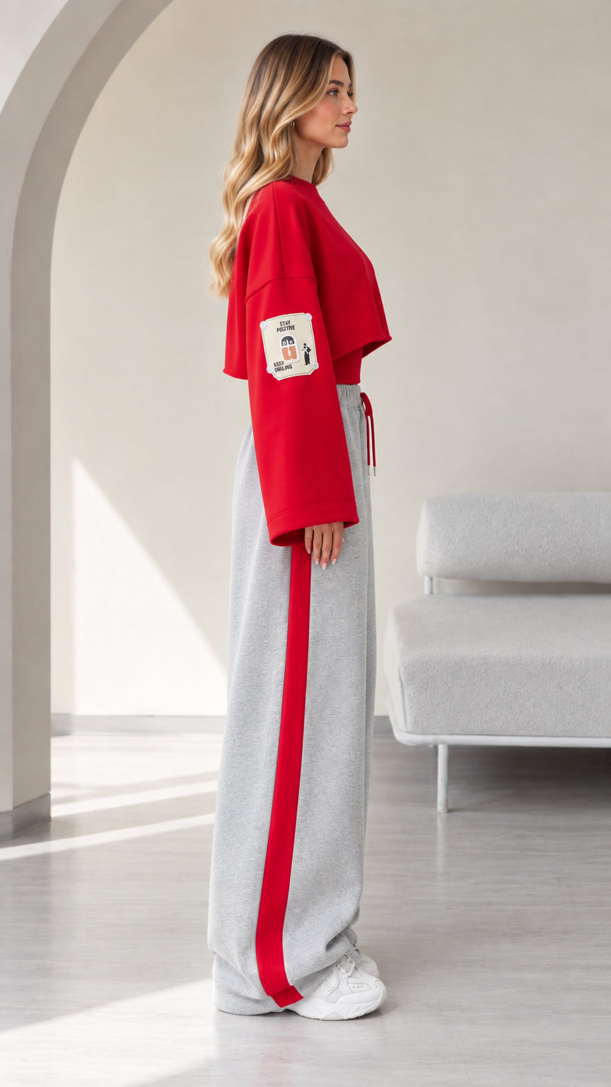Side view of model in red cropped pullover and grey wide leg joggers with red stripe