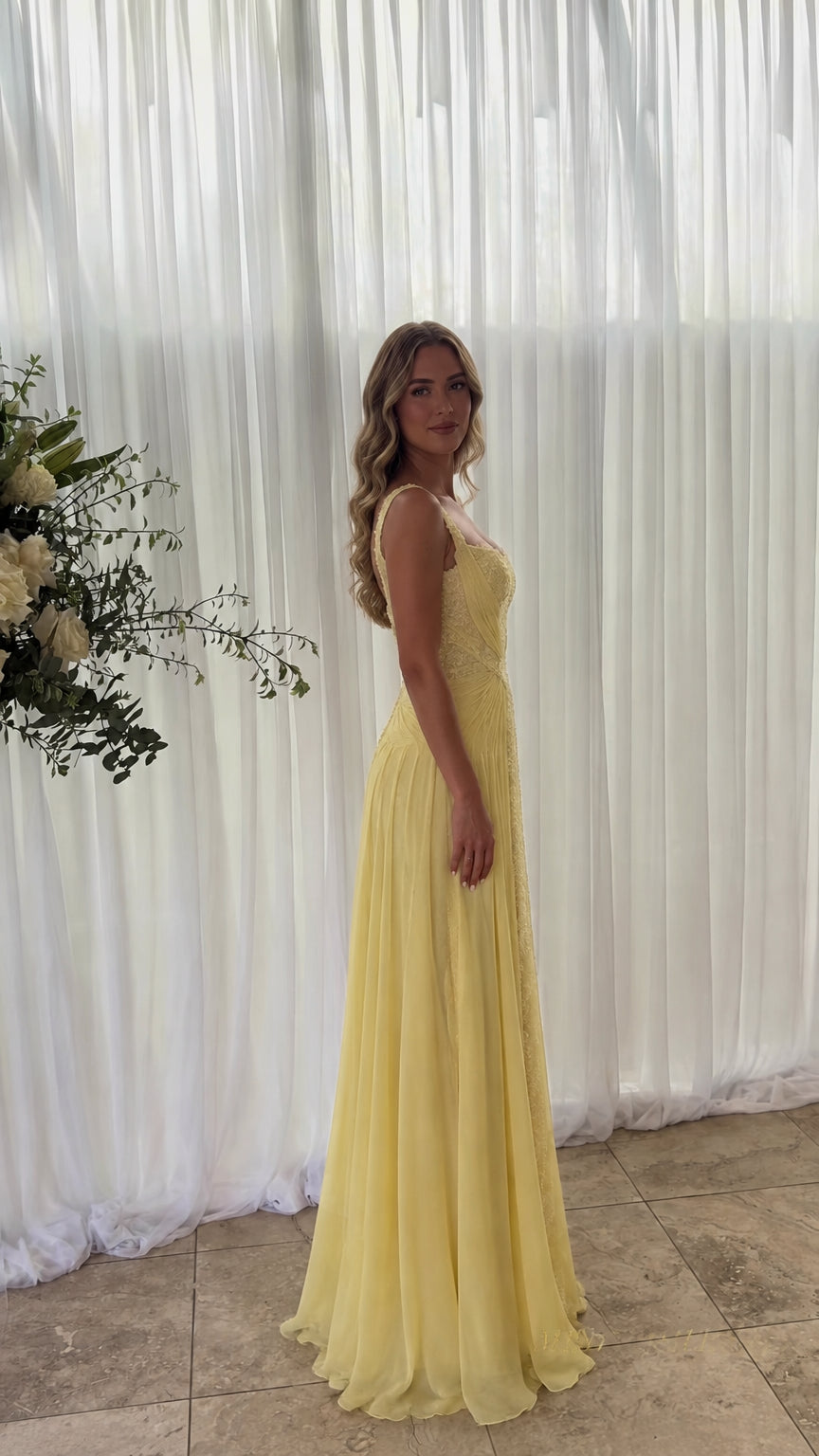 Side profile of model wearing yellow floor-length chiffon formal dress
