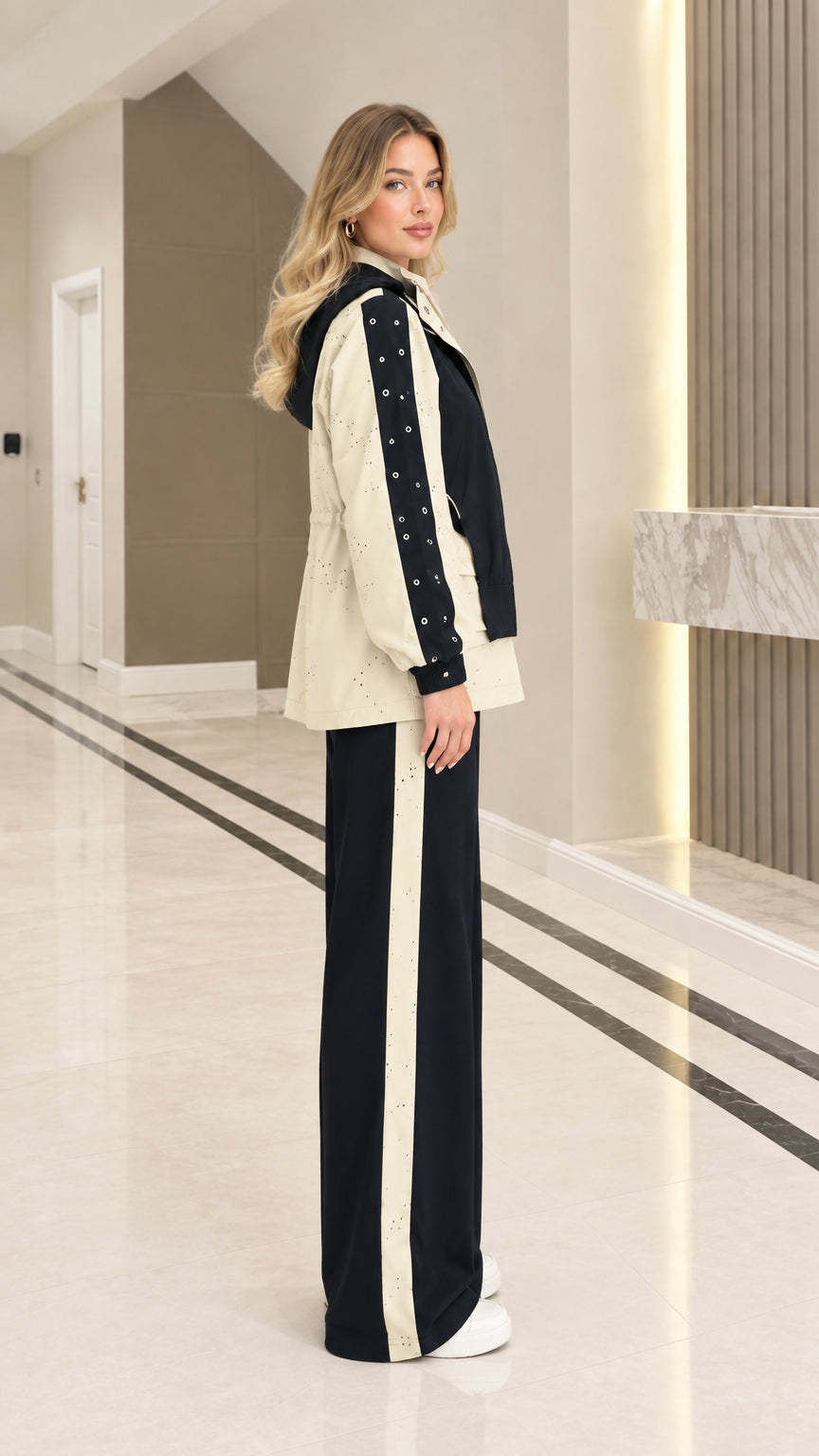 Side profile of woman wearing Black colorblock hooded tracksuit showing contrast eyelet sleeve trim
