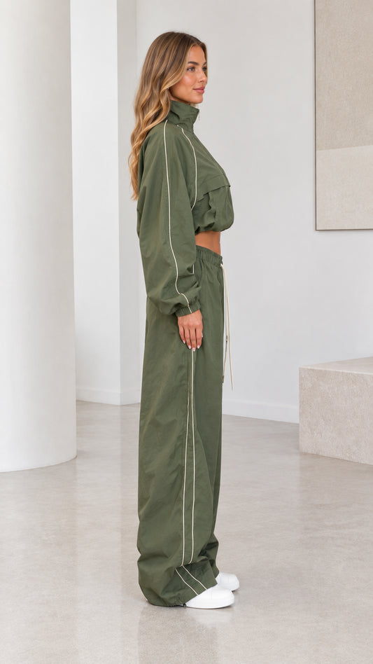 Side profile view of model in olive green tracksuit set showing piping detail