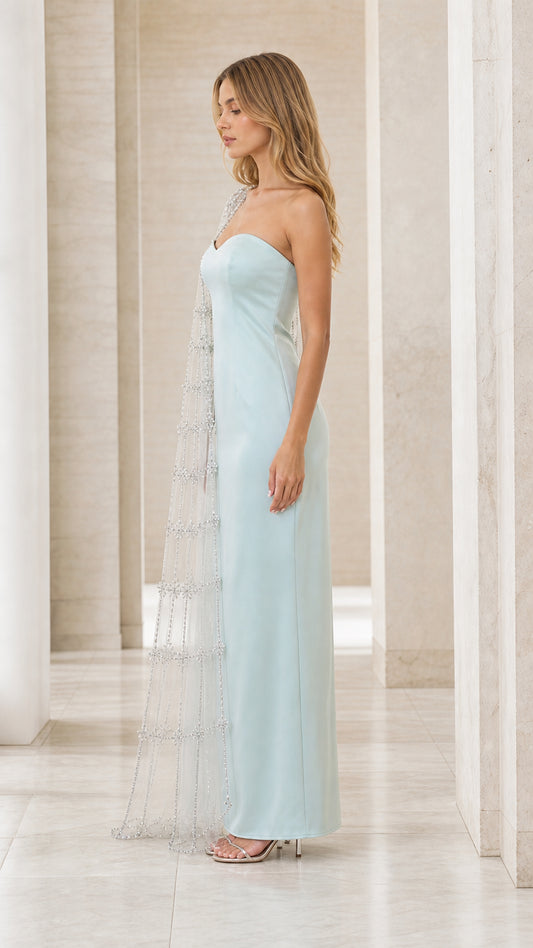 Side profile of ice blue formal gown showing the drape of the embellished cape