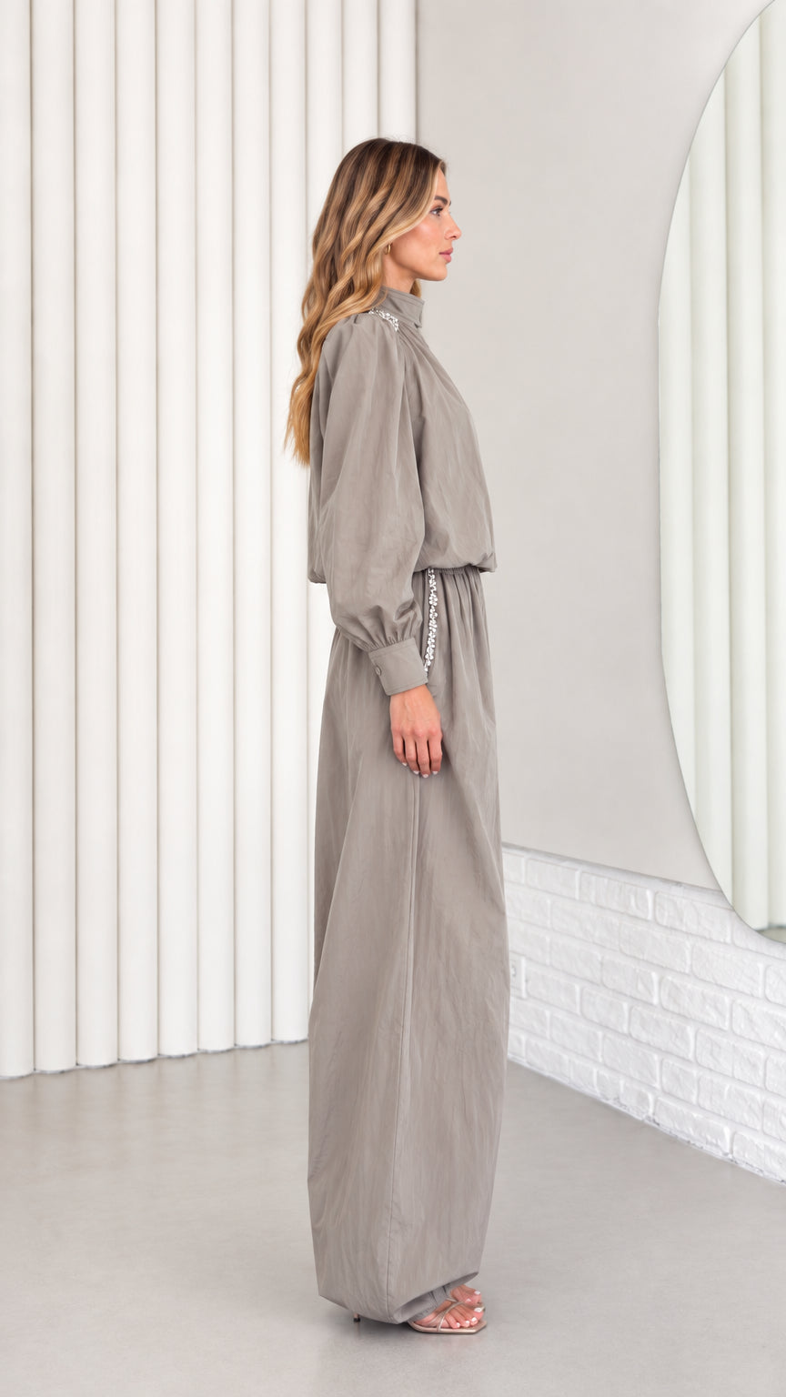 Side profile of model wearing taupe grey high-neck balloon-leg jumpsuit