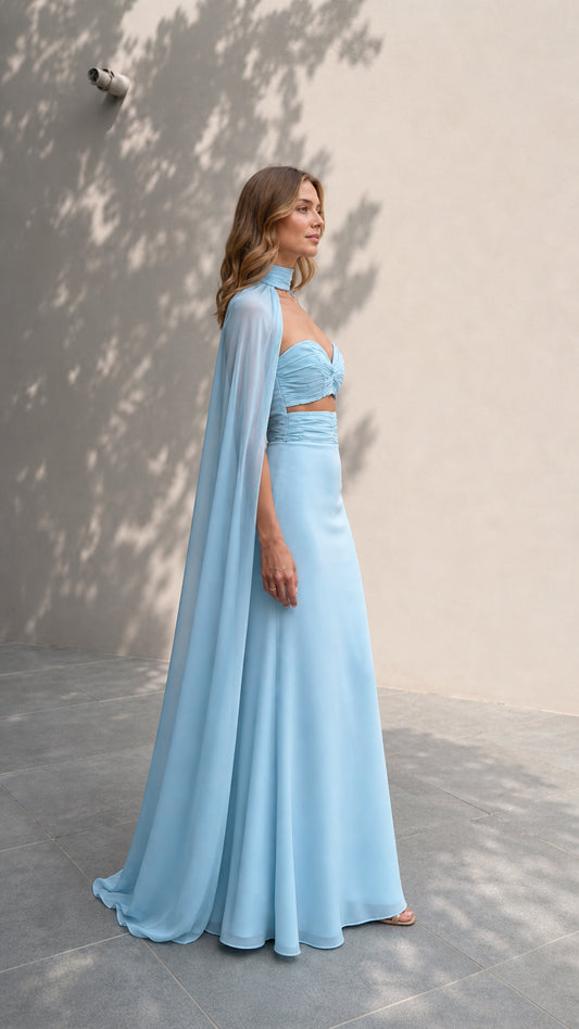 Side profile of model in light blue two-piece gown with dramatic cape