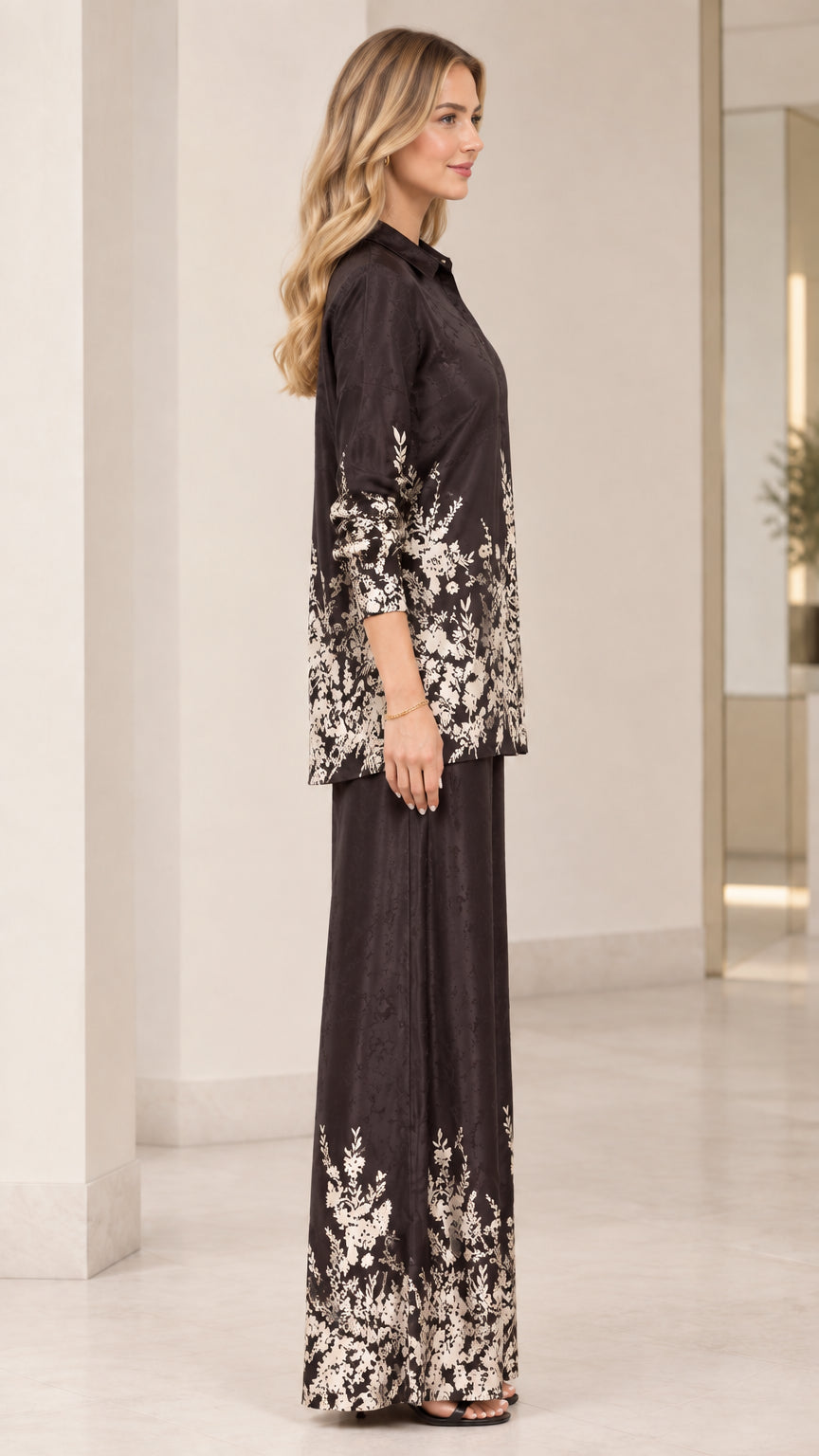 Side profile view of women's floral satin matching shirt and pant set in black