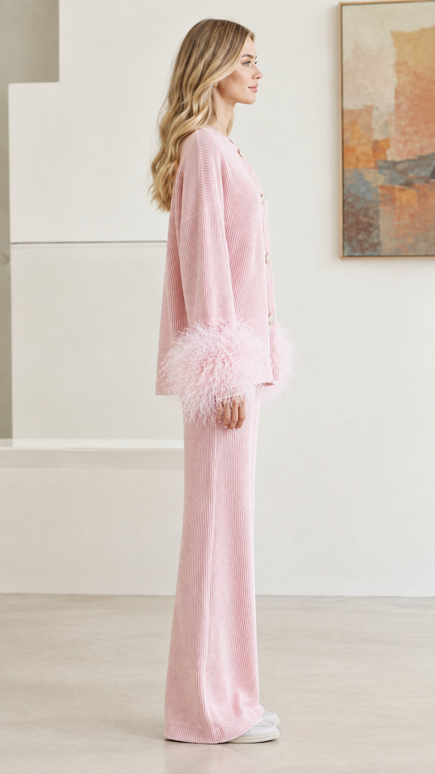 Side profile view of pastel pink knit cardigan and matching wide-leg pants with feather cuffs