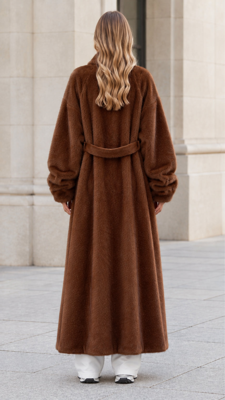 Back view of woman wearing chocolate brown plush coat highlighting the back belt detail