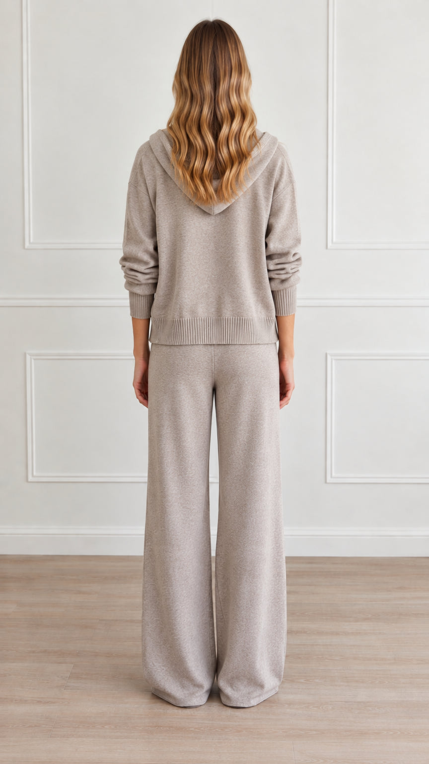 Back view of model wearing heather taupe hooded sweater and wide-leg pants
