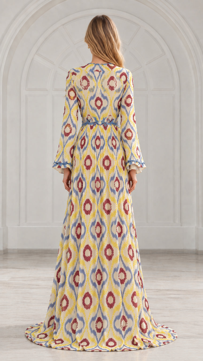Back view of yellow ikat print pleated gown showing waistline and flowing hem