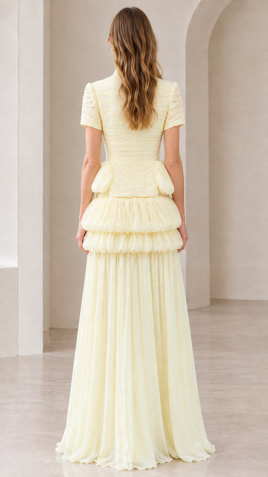 Back view of model in pale yellow tiered peplum pleated formal dress