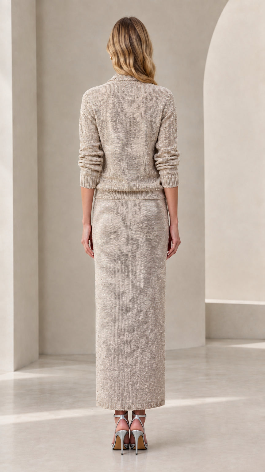 Back view of woman wearing beige knit long sleeve top and column maxi skirt