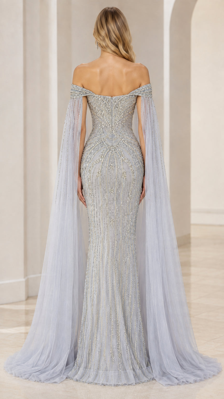 Back view of model in slate blue beaded evening dress with floor-length tulle cape