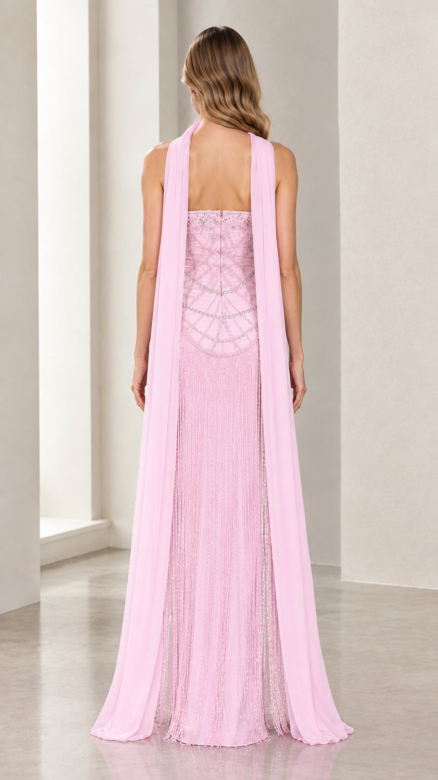 Back view of model in Blush Pink beaded evening dress highlighting long cape streamers