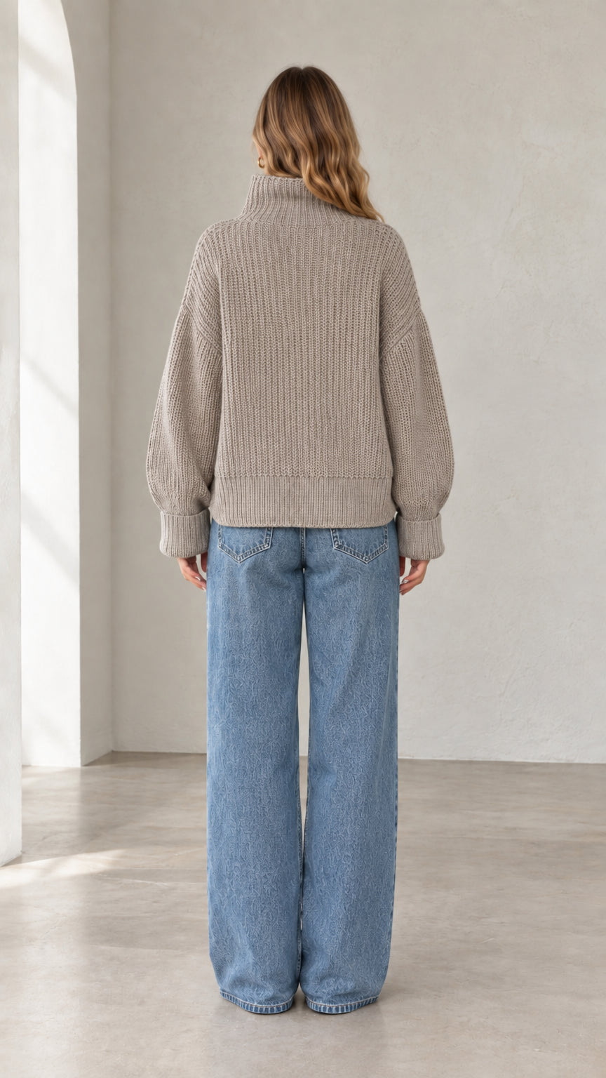 Back view of model wearing taupe ribbed knit turtleneck sweater