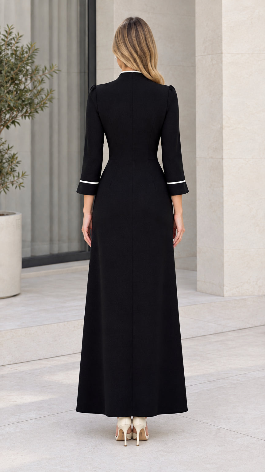 Back view of tailored black floor-length gown showing clean silhouette and sleeve piping