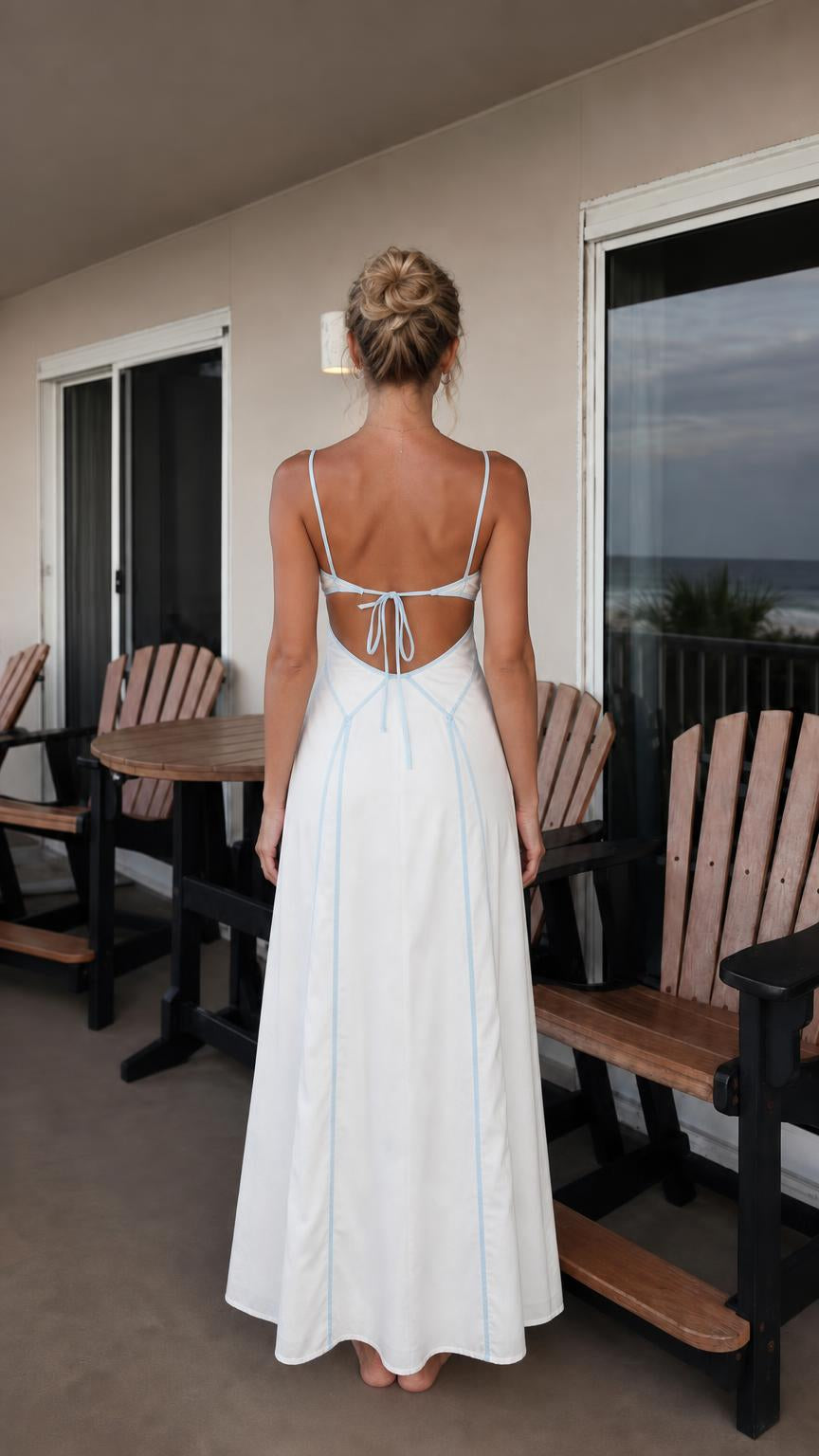 Back view of woman showing open back and tie details on white maxi dress