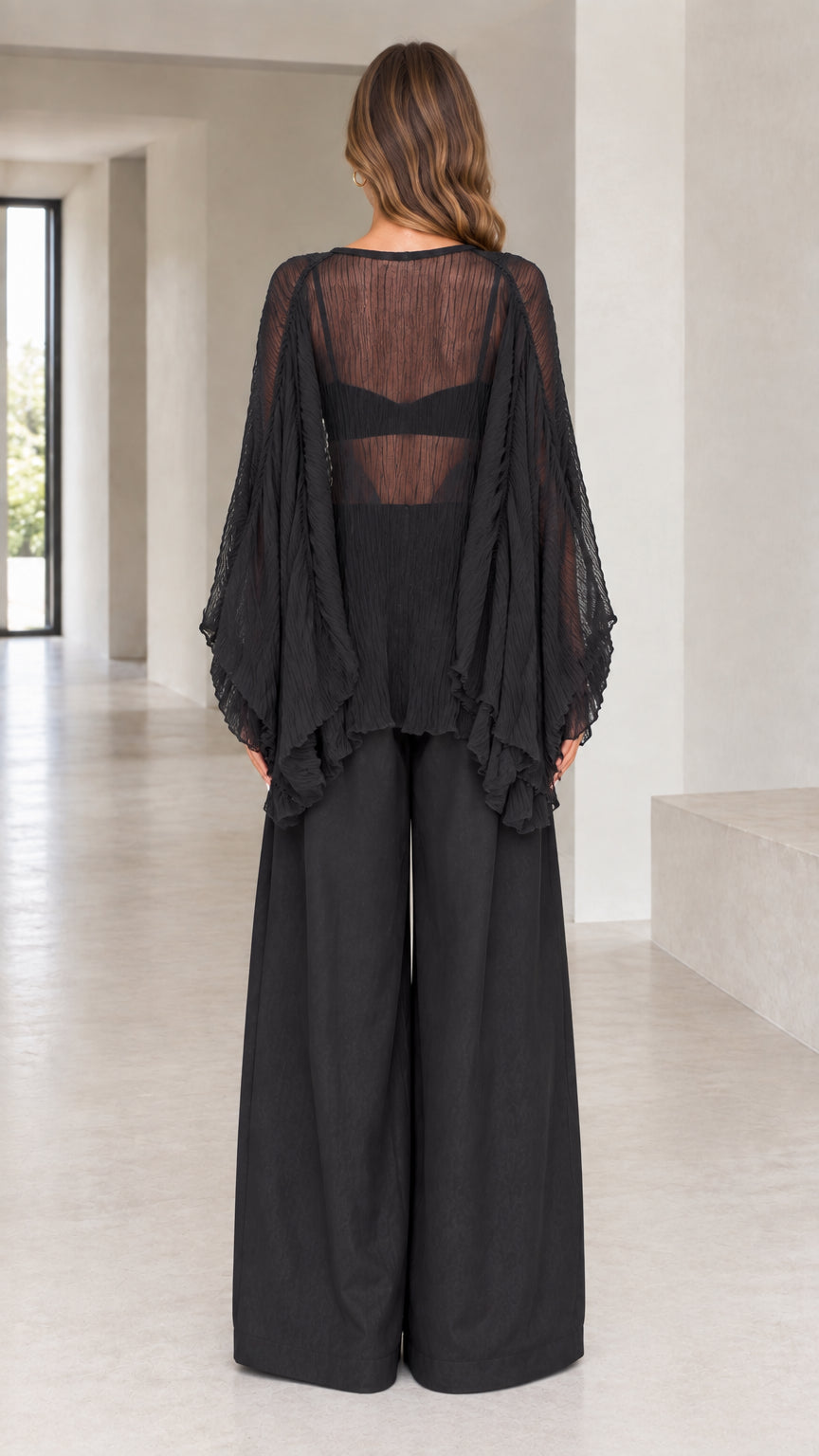 Back view of black sheer draped pleated bell sleeve blouse and flowy wide-leg trousers