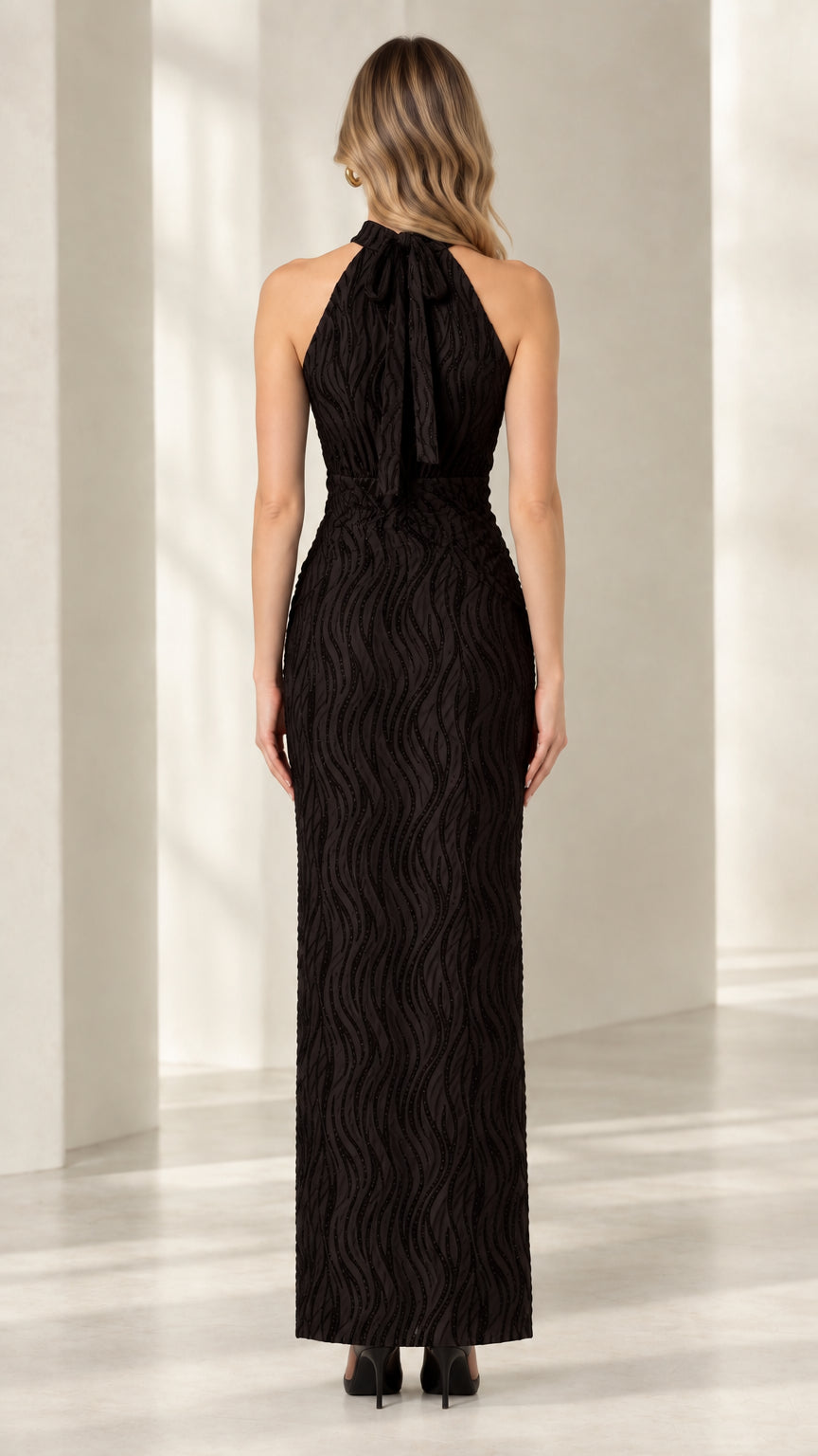 Back view of woman wearing black halter dress featuring tied back neck detail