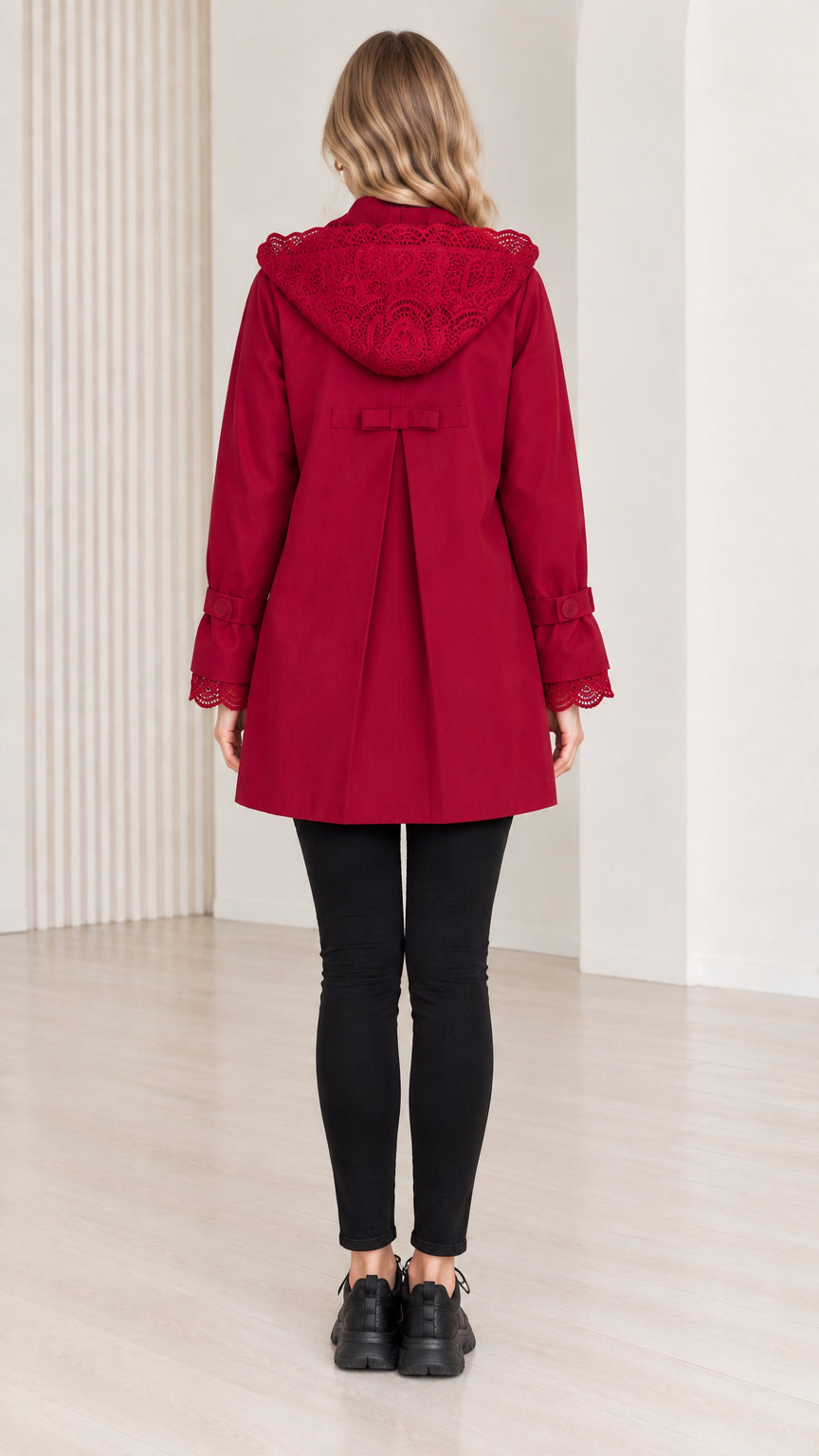 Back view of women's red hooded coat showing lace hood and box pleat
