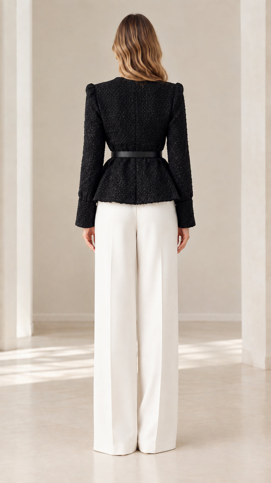 Back view of model in black collarless tweed peplum jacket and white wide-leg pants