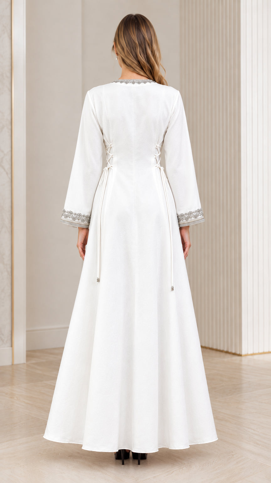 Back view of woman in elegant white long-sleeve maxi dress with waist ties