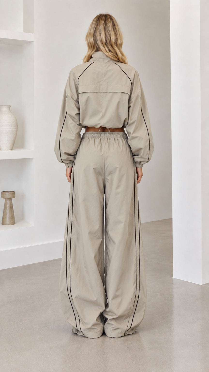 Back view of model wearing taupe cropped jacket and wide-leg parachute pants