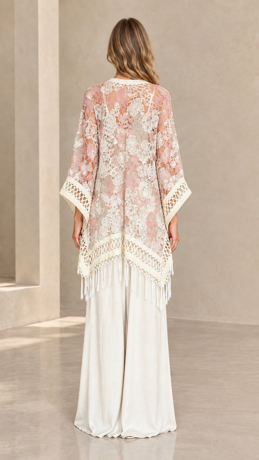 Back view of woman wearing blush pink floral lace kimono wrap with fringe trim
