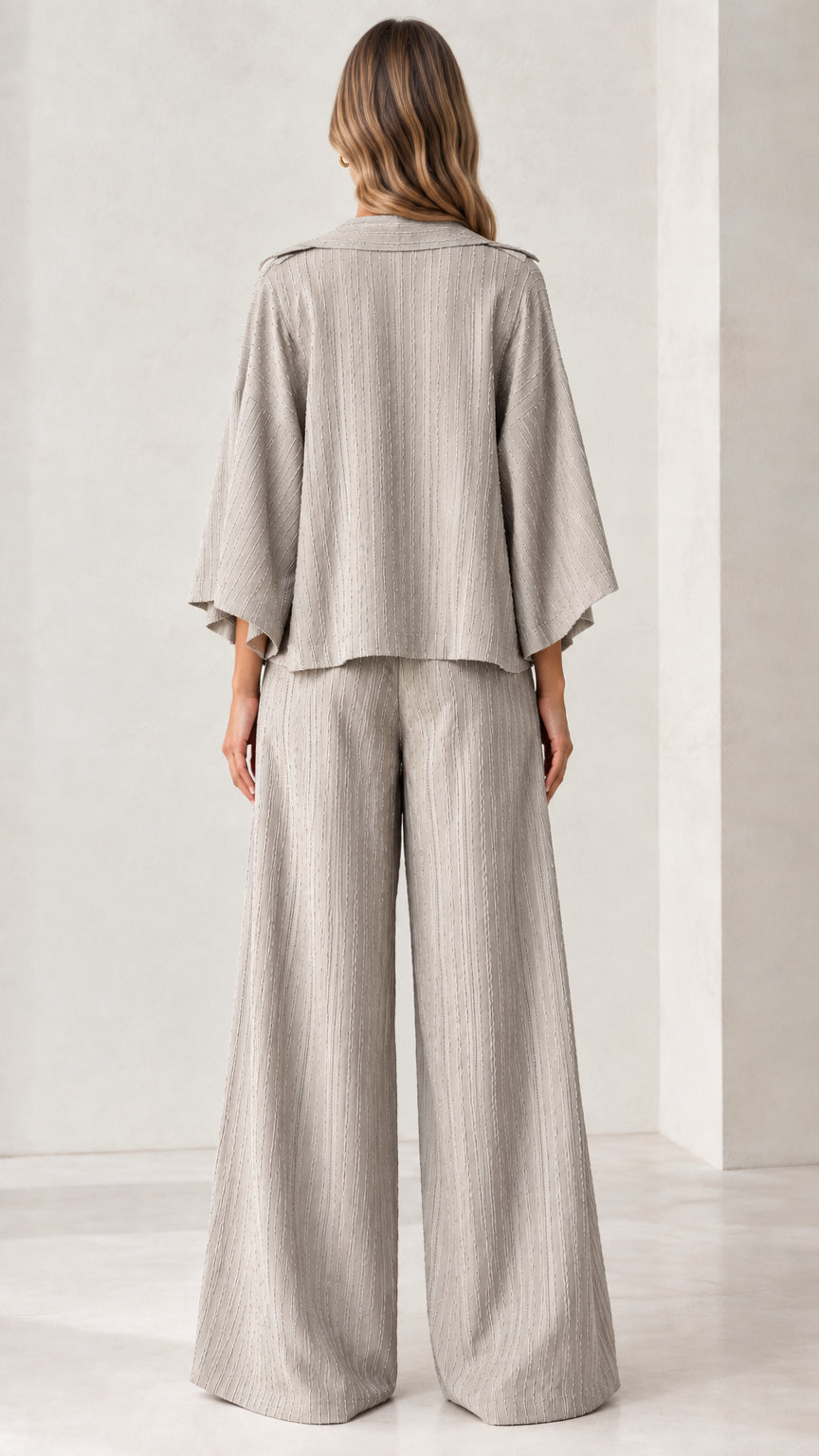 Back view of woman modeling the light grey draped jacket and wide-leg trousers