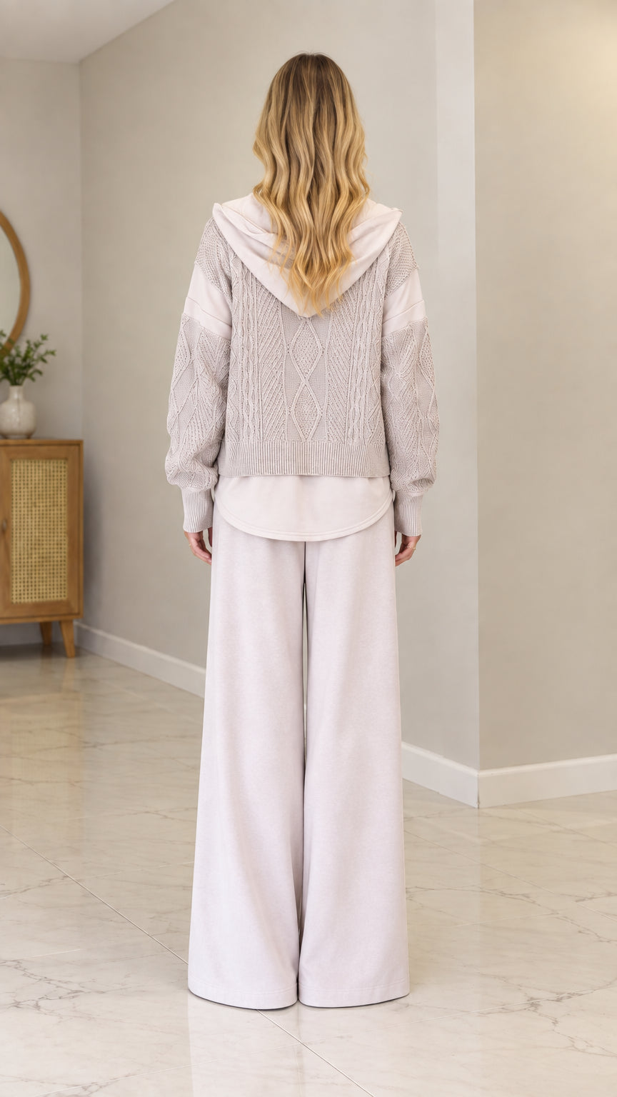 Back view of model wearing Oatmeal cable-knit hooded cardigan showing hood and hem