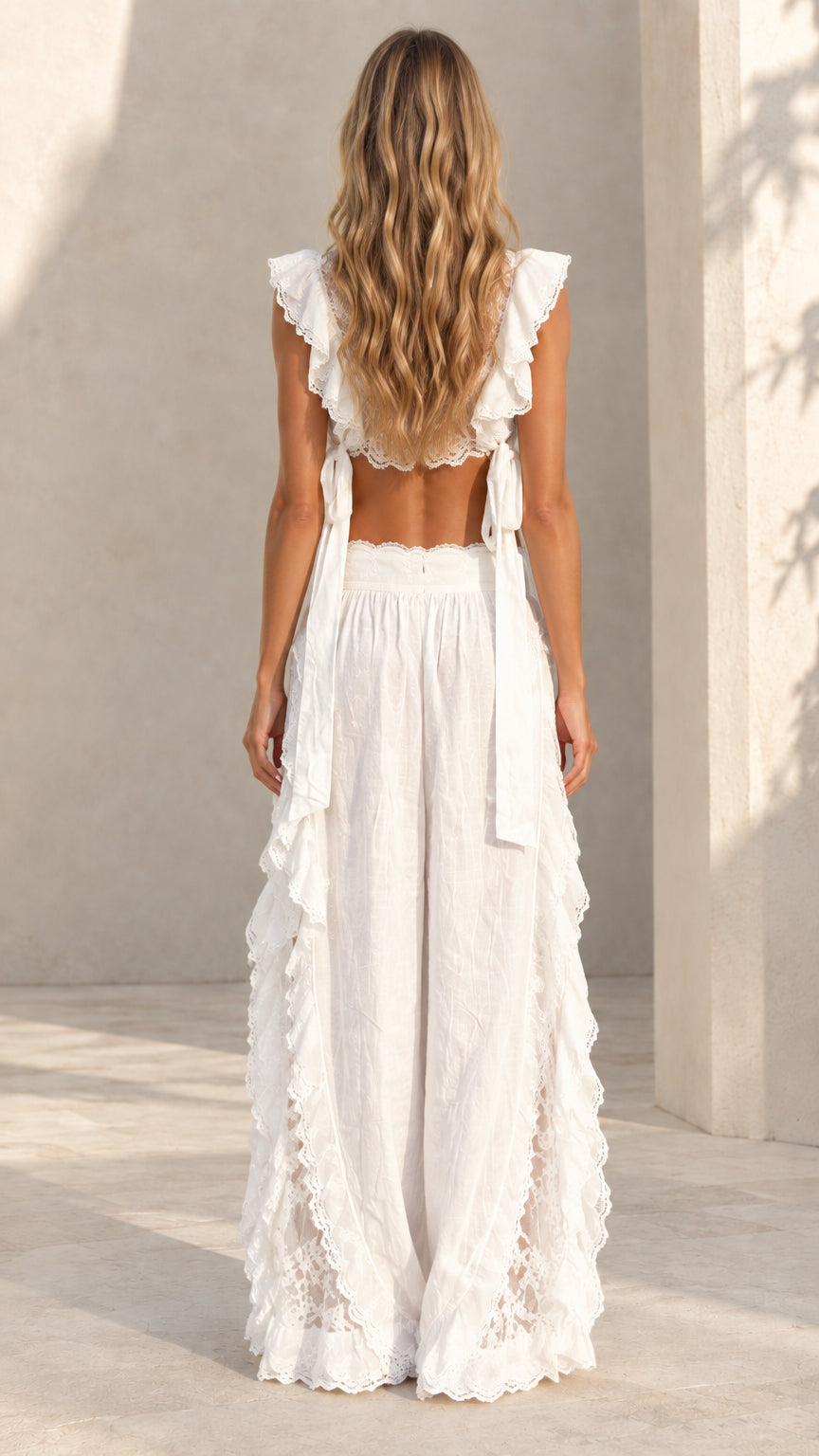 Back view of woman wearing white sleeveless crop top with open back and wide-leg pants