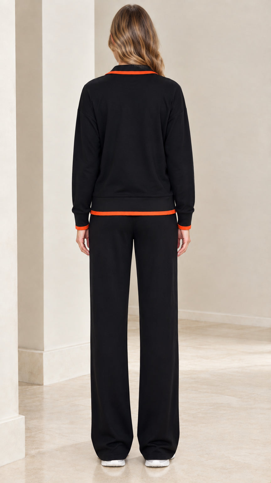 Back view of model wearing black zip-up tracksuit set