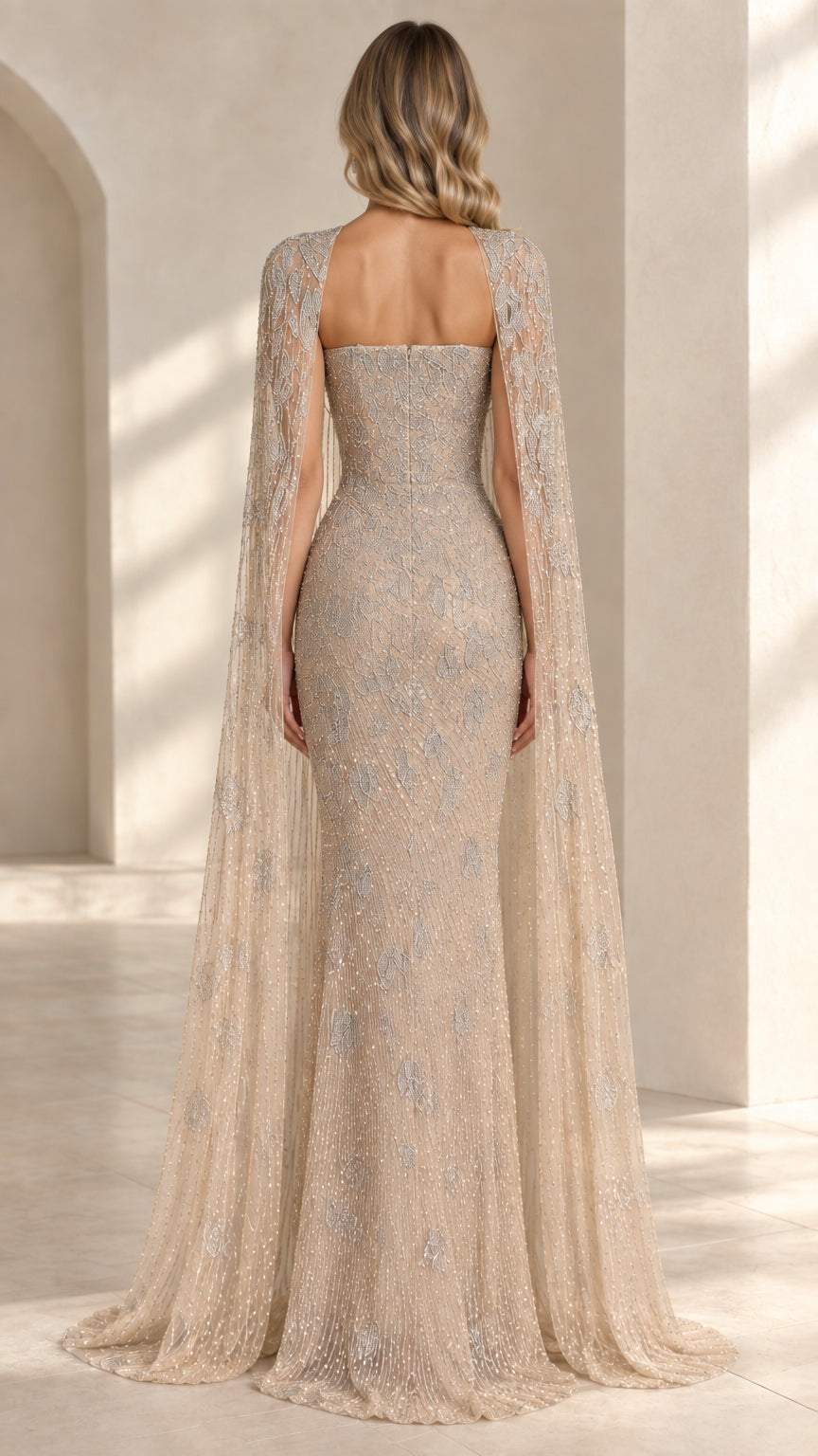 Back view of model wearing champagne strapless evening gown with long cape
