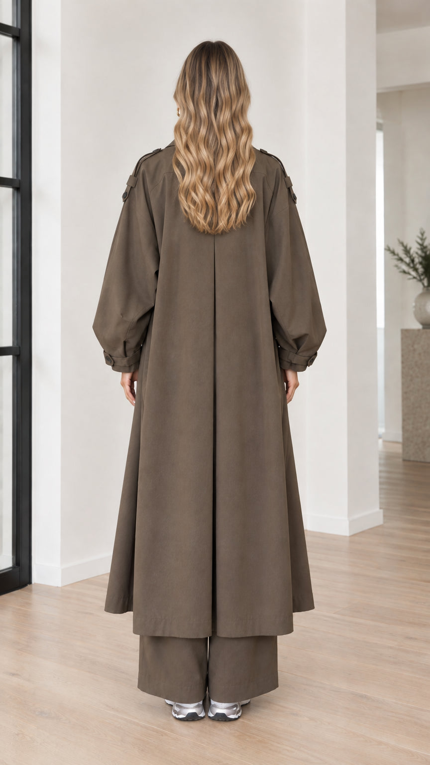 Back view of woman wearing full-length olive brown duster coat with inverted pleat