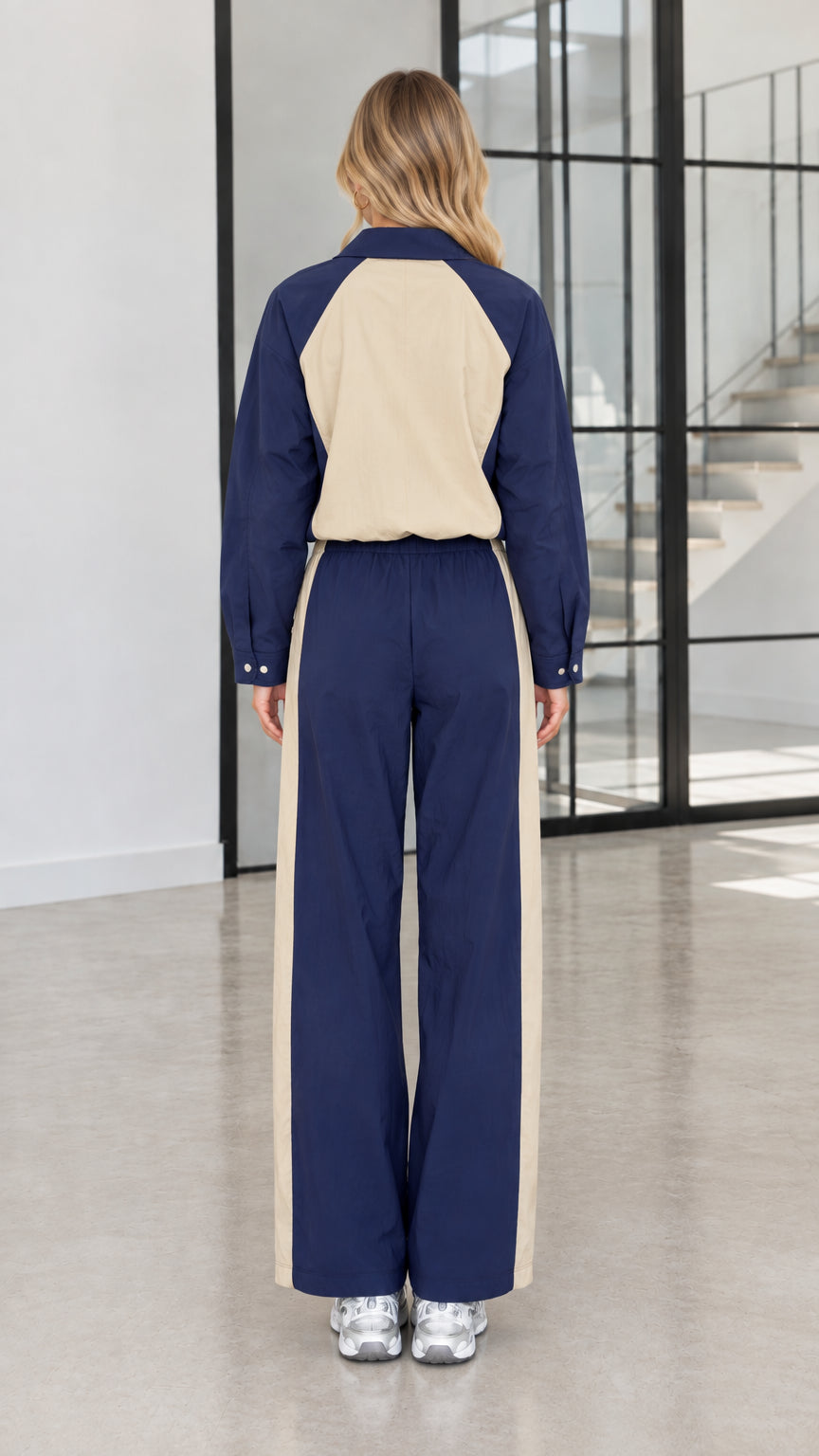 Back view of model in Navy Blue two-tone zip jacket and wide-leg trousers