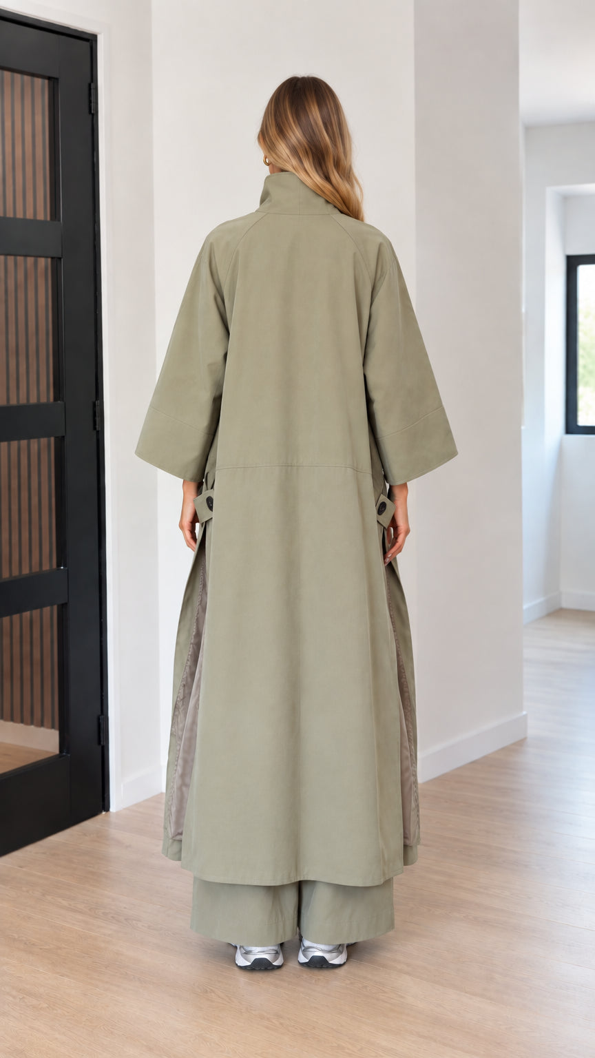 Back view of woman wearing full-length sage green cape duster coat