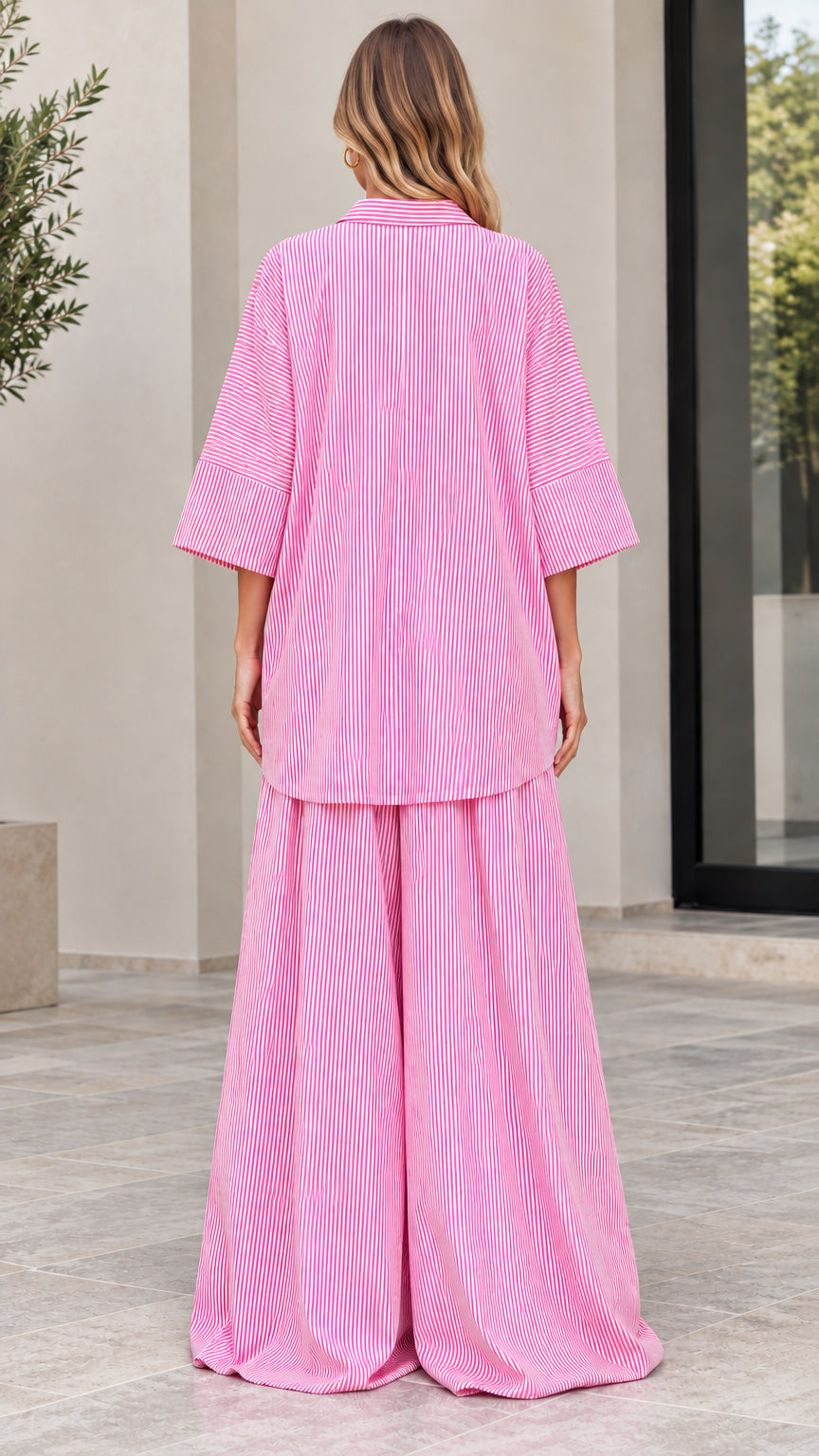 Back view of woman in relaxed pink striped collared shirt and wide-leg pants